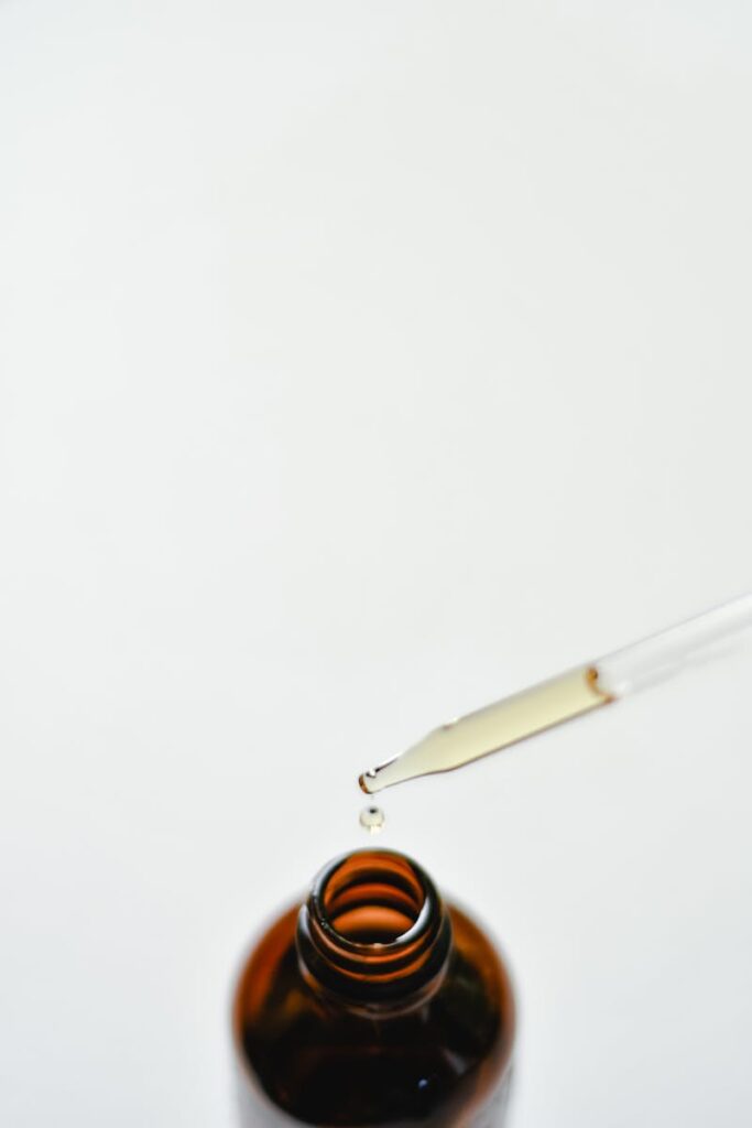 Close-up of a brown glass dropper bottle with a droplet, perfect for essential oils or medicine use.